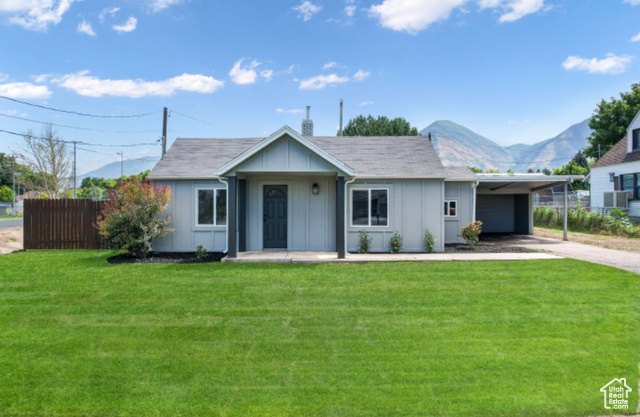 View of front of property with a carport, a mountain view, and a front yard