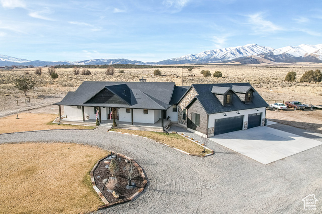 View of front of property featuring a mountain view, a porch, and a garage