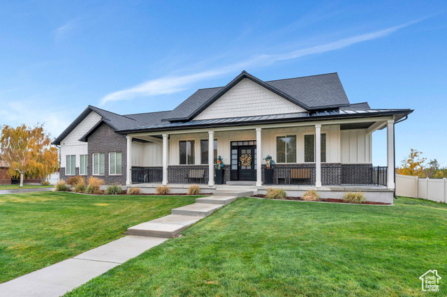 View of front of property with covered porch and a front lawn