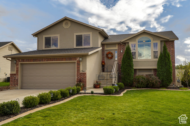 Split level home featuring a garage and a front lawn