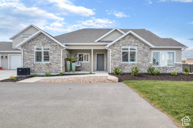 Craftsman house featuring a porch, a garage, central air condition unit, and a front lawn