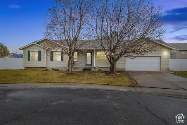 Ranch-style home featuring a garage and a lawn