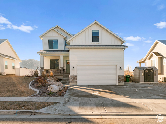 View of front of house with a mountain view, a garage, a storage shed, and central air condition unit