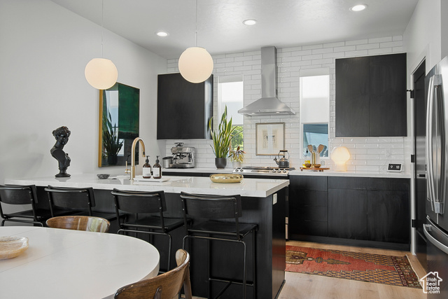 Contemporary elegant chef's kitchen featuring quartz countertops, decorative light fixtures, stainless steel GE appliances, gas range, direct-vent hood, farmhouse sink, backsplash, and sleek flat-panel cabinetry