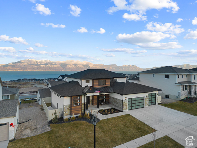 View of front of home with a front yard, a garage, and a water and mountain view