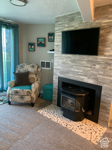 Carpeted living room with a wood stove and a textured ceiling