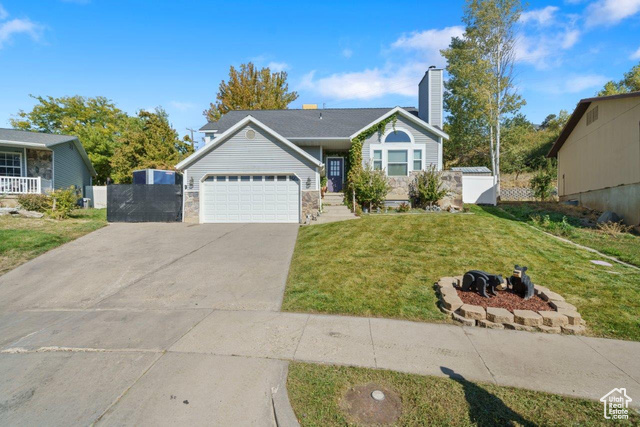 View of front facade featuring a garage and a front lawn