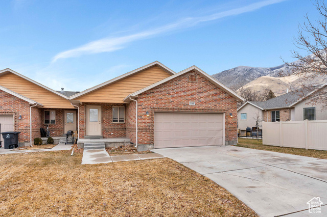 Single story home with a mountain view, a garage, and a front lawn