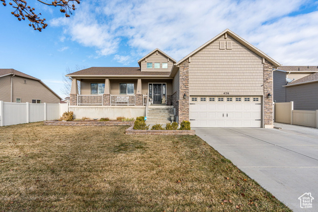 View of front of home featuring covered porch, a front yard, and a garage