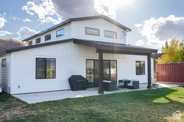 Back of house with outdoor lounge area, a patio area, and a lawn