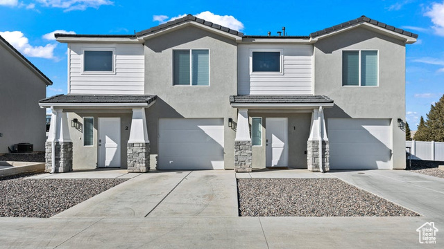 View of front of home with central air condition unit and a garage