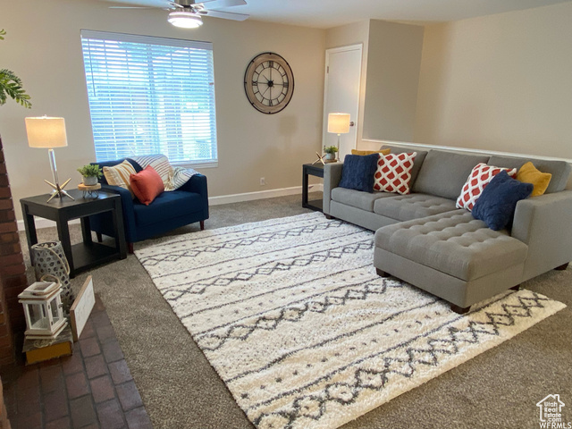 Living room with carpet flooring and ceiling fan. Staged