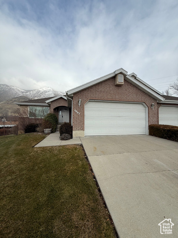 Ranch-style home with a mountain view, a garage, and a front lawn