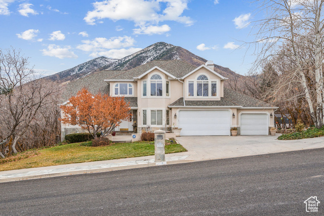 Front facade featuring a mountain view, a garage, and a front yard