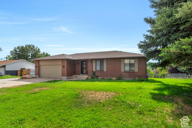 Single story home with a garage and a front lawn