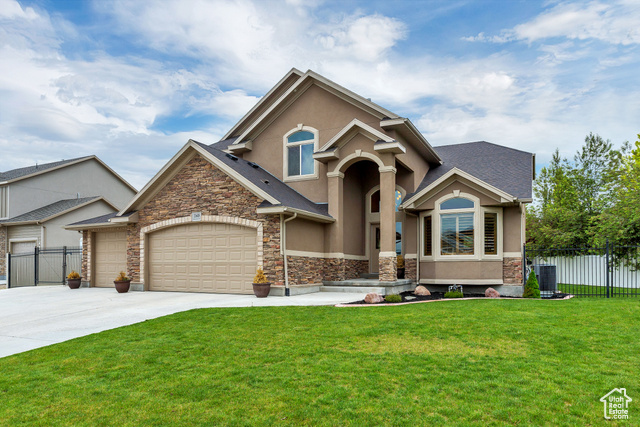 View of front facade with a front lawn, central AC unit, and a garage