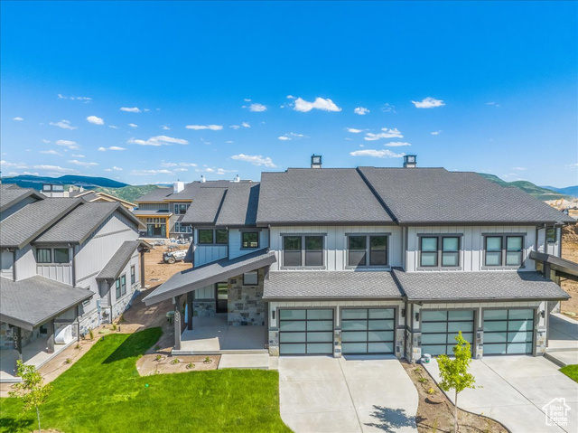 View of property featuring a mountain view, a front yard, and a garage