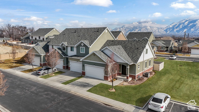 View of front of property with a garage, a mountain view, and a front lawn