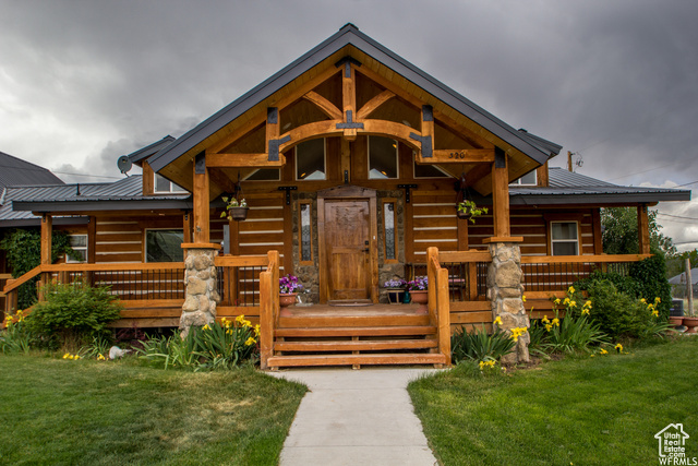 Log-style house featuring covered porch and a front lawn