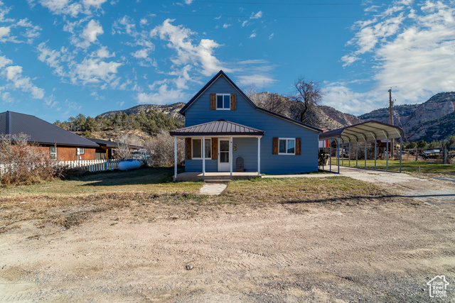 View of front of property featuring covered porch, a mountain view, and a carport