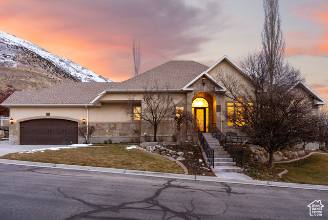 View of front of home featuring a mountain view, a garage, and a lawn