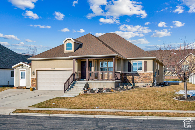 View of front of property with a garage, covered porch, and a front lawn