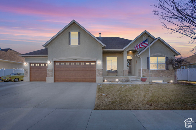 View of front facade featuring a garage and a yard