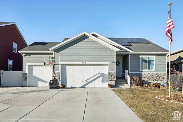 View of front of home with a garage, a front lawn, and solar panels