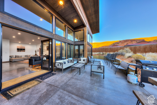 Patio terrace at dusk with a mountain view, an outdoor hangout area, and a grill