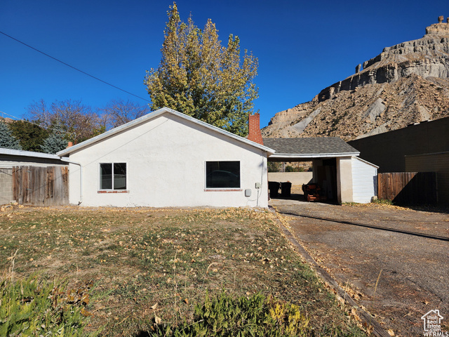 View of side of property featuring a carport and a lawn