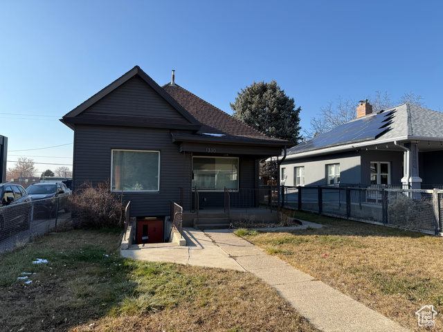 Back of property featuring a patio area, a lawn, and solar panels