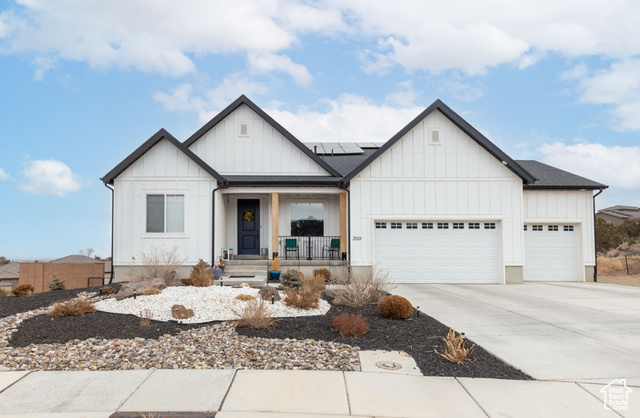 Modern farmhouse style home featuring a garage, solar panels, and a porch