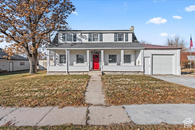 View of front facade featuring a garage, a front yard, and covered porch