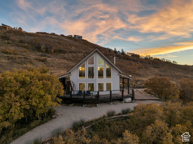 Back house at dusk featuring a deck with mountain view