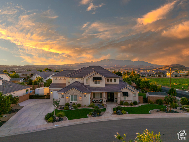 View of front of house with a garage, a mountain view, and a lawn