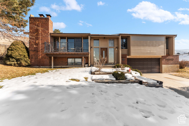 View of front of home with a garage and a balcony