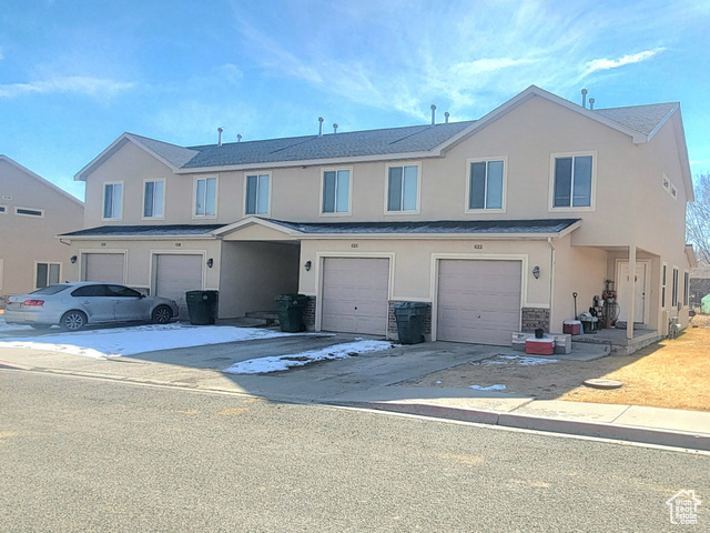 Multi unit property featuring driveway, a garage, and stucco siding