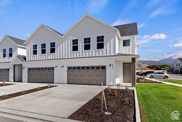 View of front of home with an attached garage, a mountain view, board and batten siding, and roof with shingles