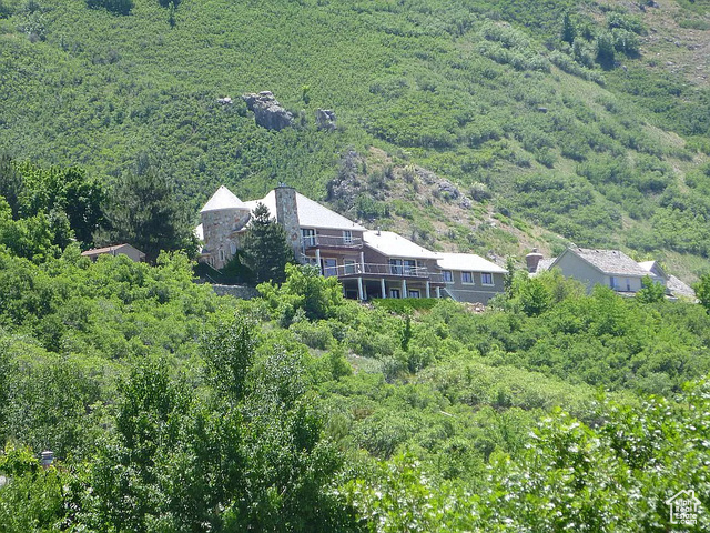 This French chateau style home was originally constructed in 1979, as a an entertaining showcase, for Glen A. Larson, baritone singer of the late-1950s pop group, The Four Preps, and later the director of the TV programs Battlestar Galactica, Magnum PI and Knight Rider. Glen had his choice of any lot in the subdivision, and he chose this lot because it was huge, had the largest usable area, as well the best views, and afforded a level entrance from the street to the garage. The home was completely rebuilt from 2000 to 2003 to be even more elegantly stunning. Most of the electrical was replaced, most of the plumbing was replaced, and the entire structure was stripped down to the exterior plywood sheeting and finished with tumbled artisan brick, cast concrete trim around the windows and doors, and quartz stone on the chimney and entry turret. Even the pillars of the wall along the front of the property are covered with quartz stone. There is not one bit of fake "cultured" stone anywhere. The property features stunning mountain and valley views, mature landscaping, multiple water features, and multiple hosting spaces. The 1.7-acre lot has an amazing three hundred fifty feet of street frontage, and includes a private park, with a basketball court, playground, an 18' x 40' in-ground, gunite pool with a hot tub, diving board and slide, that was recently refurbished . There are no large lots with spectacular views, such as this, available today anywhere in Utah Valley. The lot, alone, which is more than three times the size of an ordinary lot in this subdivision, and which features truly spectacular views, has to be worth at least $2,000,000. This is the quintessential home for elegant entertaining. Three wrought iron gates guard access to the property. The windows and entry doors of the home have cast concrete trim, and those on the main floor have small replicas of the sun stones on the Nauvoo Temple. There is 1500 square feet of decking for outdoor parties and dancing. The sellers really obsessed over the remodel of the kitchen. Everything in it is first class, from the large, Kitchenaid, cabinet deep refrigerator/freezer, the Kraft-Maid cherry cabinets with dove-tailed drawer joints, the hickory floor, dual Kitchenaid dish washers, the Heatilator three-sided fireplace, the granite countertops, the island, dual LG microwave ovens, to the LG double oven. The kitchen, 43' x 25' living room, the 30' x 17' master bedroom, the two decks, and even the 4-car garage have views of the Utah Valley and Utah Lake to die for. The living room and family room off the kitchen each have 10' ceiling that are coffered and backlit around the perimeter. The formal dining room has a 9' ceiling that is coffered and backlit around the perimeter. There is an elegant 25' x 15' music room/office with hydronic floor heating on the main floor with a 9' coffered, wainscoted ceiling, crystal basket chandeliers, walls with intricate paneling and moldings. There are elegant crown moldings, door and window trims through the interior. Nearly every room and the decks have stereo speakers that are connected to an in-house music system which will remain with the home. A Lindhaus whole-house central vacuum system is installed. An in-ground rectangular trampoline and the 18' x 40' pool with hot tub, diving board and water slide also have spectacular views of the valley and lake. The pool house has a covered eating area and a 3/4 bath. The 30' x 22' theater has 14 seats on three levels, a 110" screen, and a high-definition projector. The main floor entrance hallway and the kitchen have a total of 13 stained-glass lighting panels. In fact, the 20'-tall entry turret has an 18'-diameter lighted, stained glass ceiling. The entry, entry hallway and formal dining room are finished with heated marble tile with black granite accents in elegant patterns. All of the bathrooms have either marble or black granite tile. The master bathroom and basement bathroom have heated floors.The