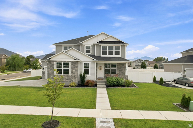 Two-story residence featuring stone and siding exterior, an attached garage, and a concrete pathway leading to the entrance